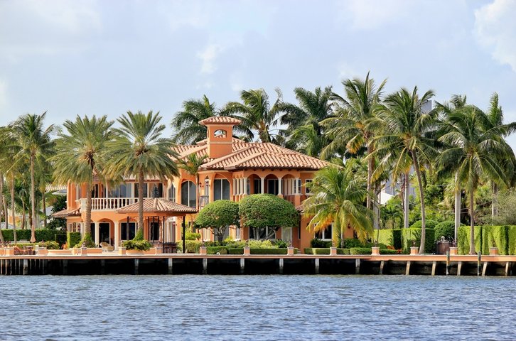 Luxury waterfront Mediterranean-style home with terracotta roof and palm trees along the shoreline of Anna Maria Island, Florida
