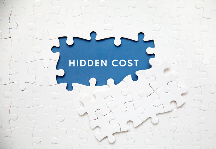White jigsaw puzzle pieces revealing the words 'HIDDEN COST' on a blue background, symbolizing unseen expenses in empty homes